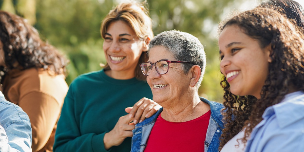 Three women standing in group laughing 
