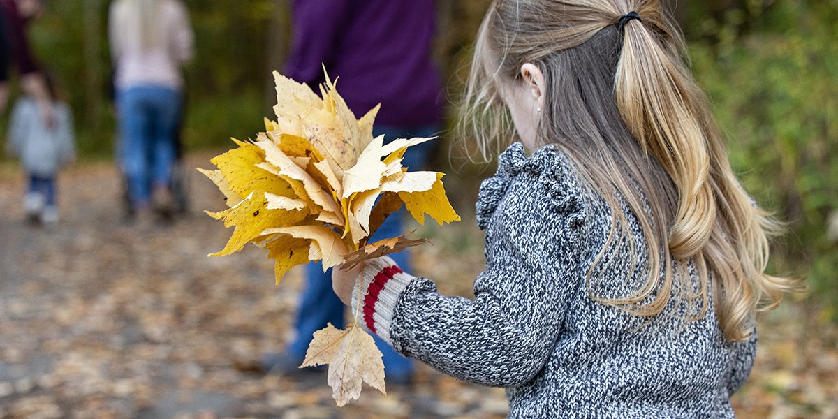 Little girl with blonde hair holding leaves