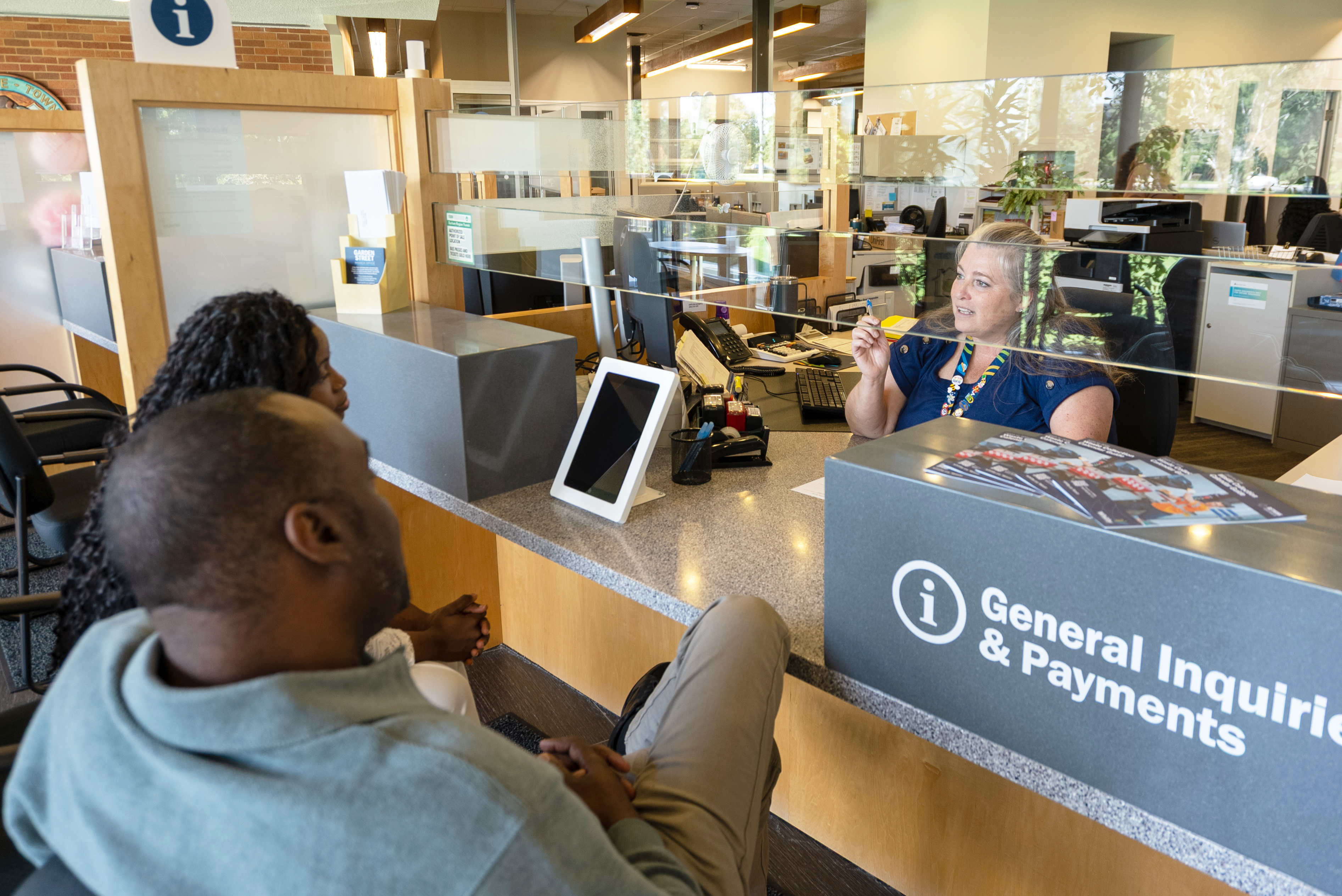 People speaking with a clerk at the front desk of Town Hall