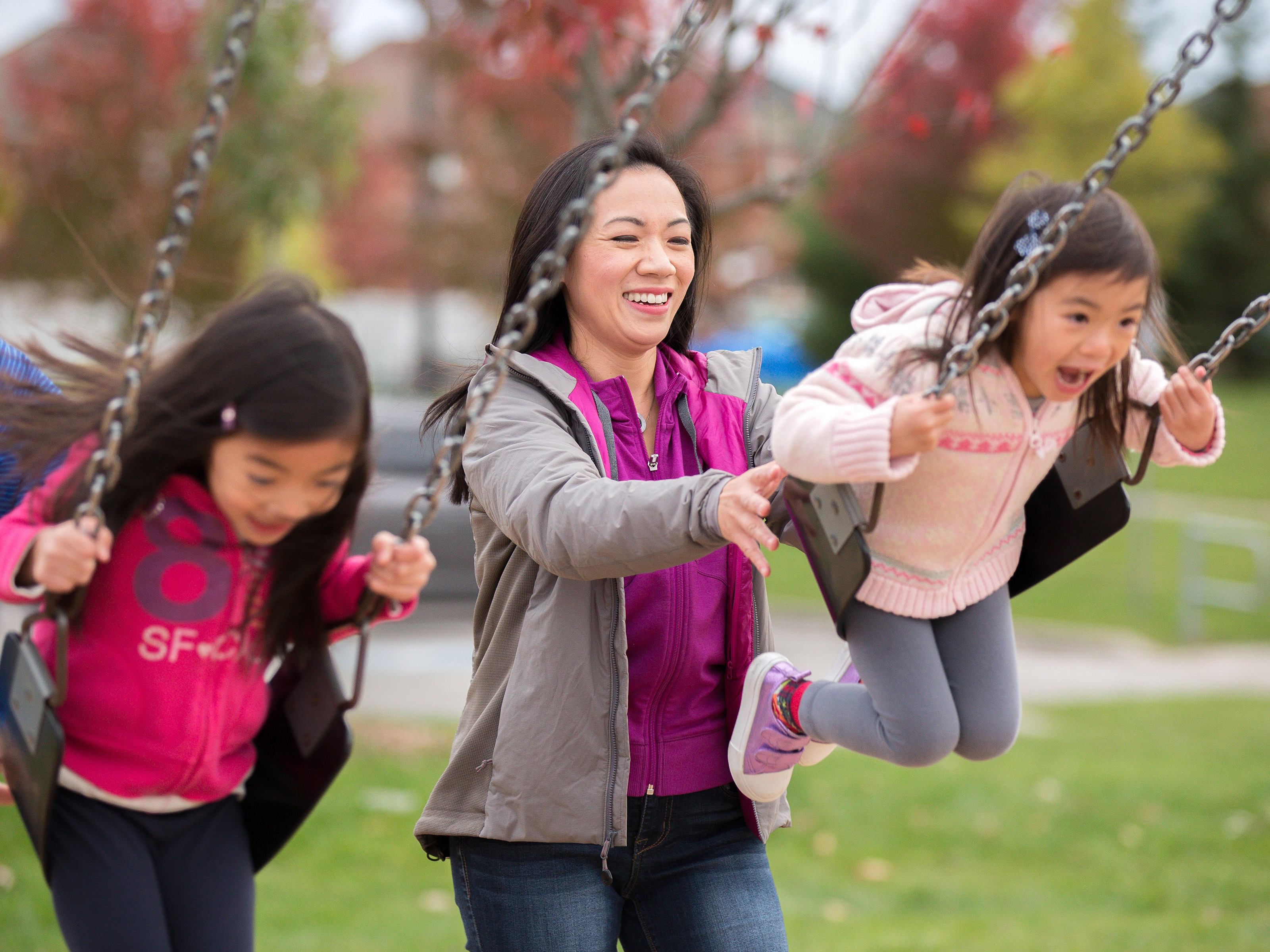 A woman pushing kids on swings