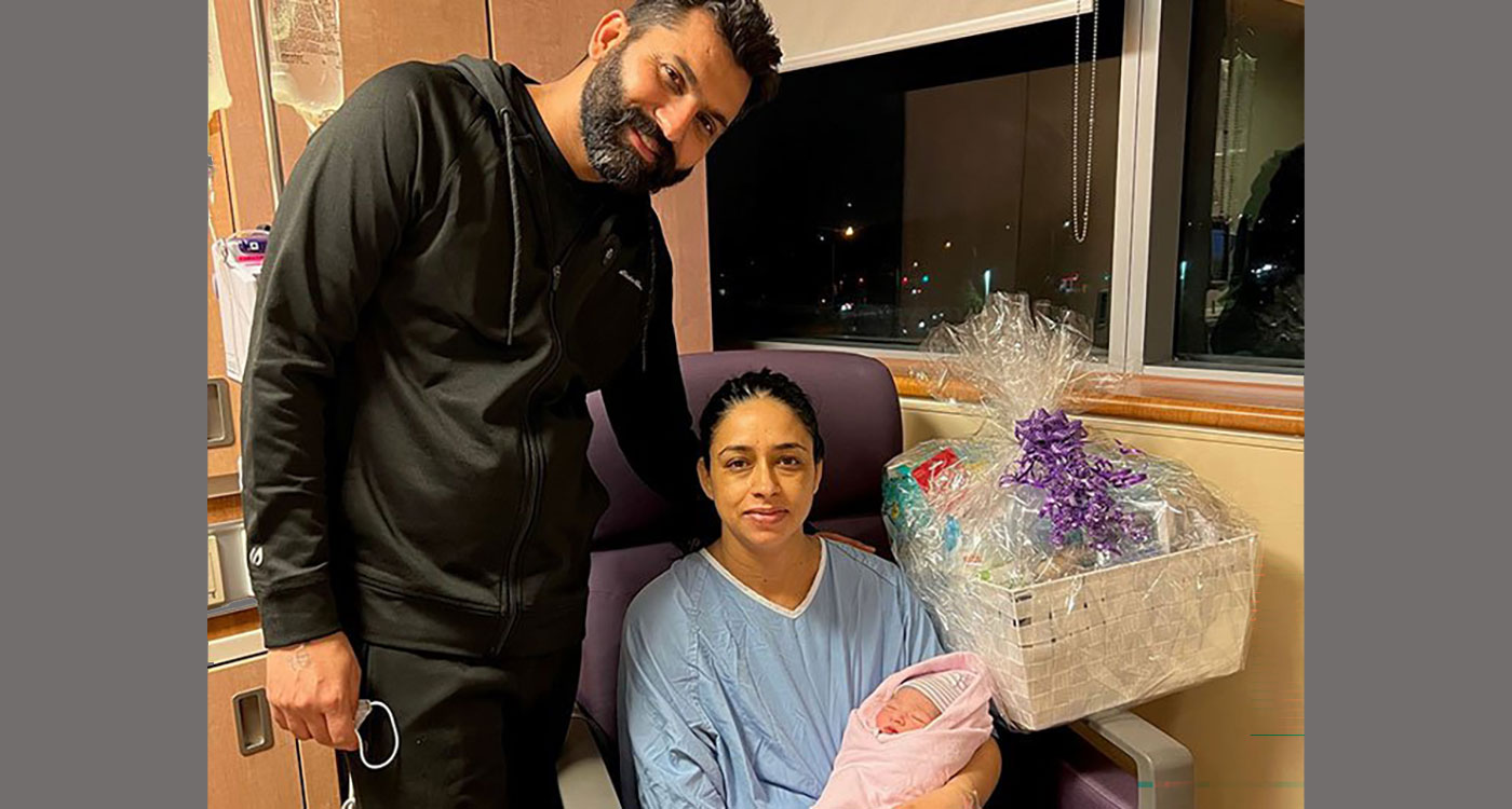 (l-r): Yadwinder Singh Bajwa stands beside Jasmeet Kaur Bajwa who is seated and holding a baby girl